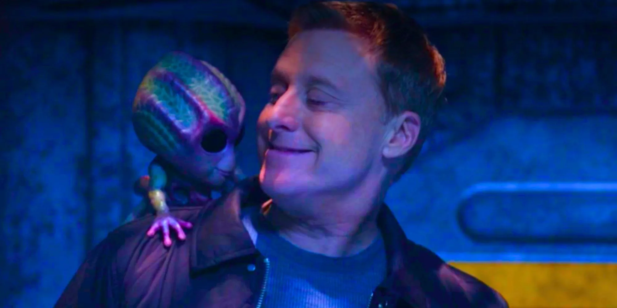 Alan Tudyk nei panni di Harry in Resident Alien sorride a Bridget che si siede sulla sua spalla