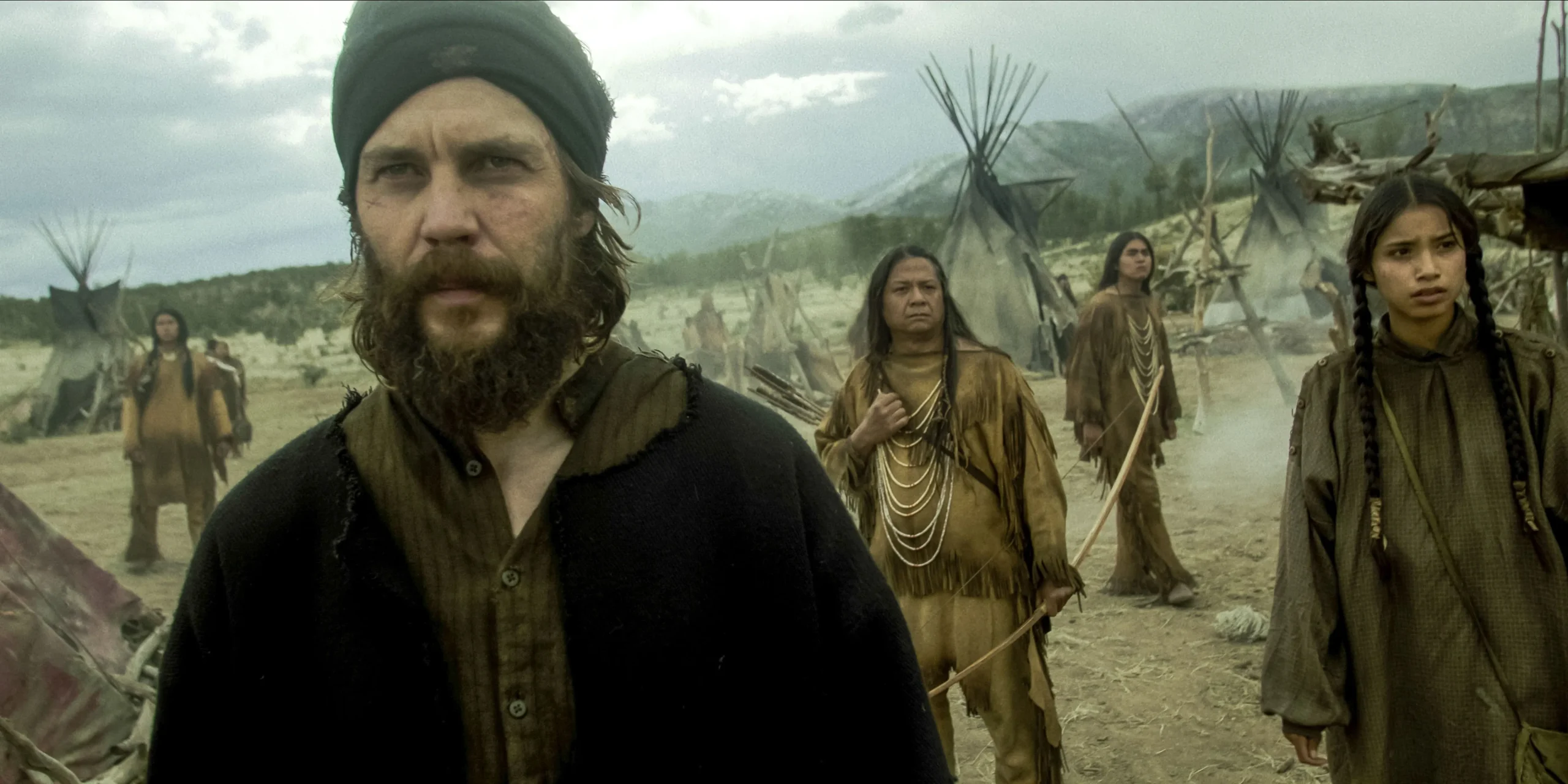 Taylor Kitsch's Isaac intensely observing in a Paiute camp from American Primeval Taylor Kitsch's Isaac intensely observing in a Paiute camp from American Primeval
