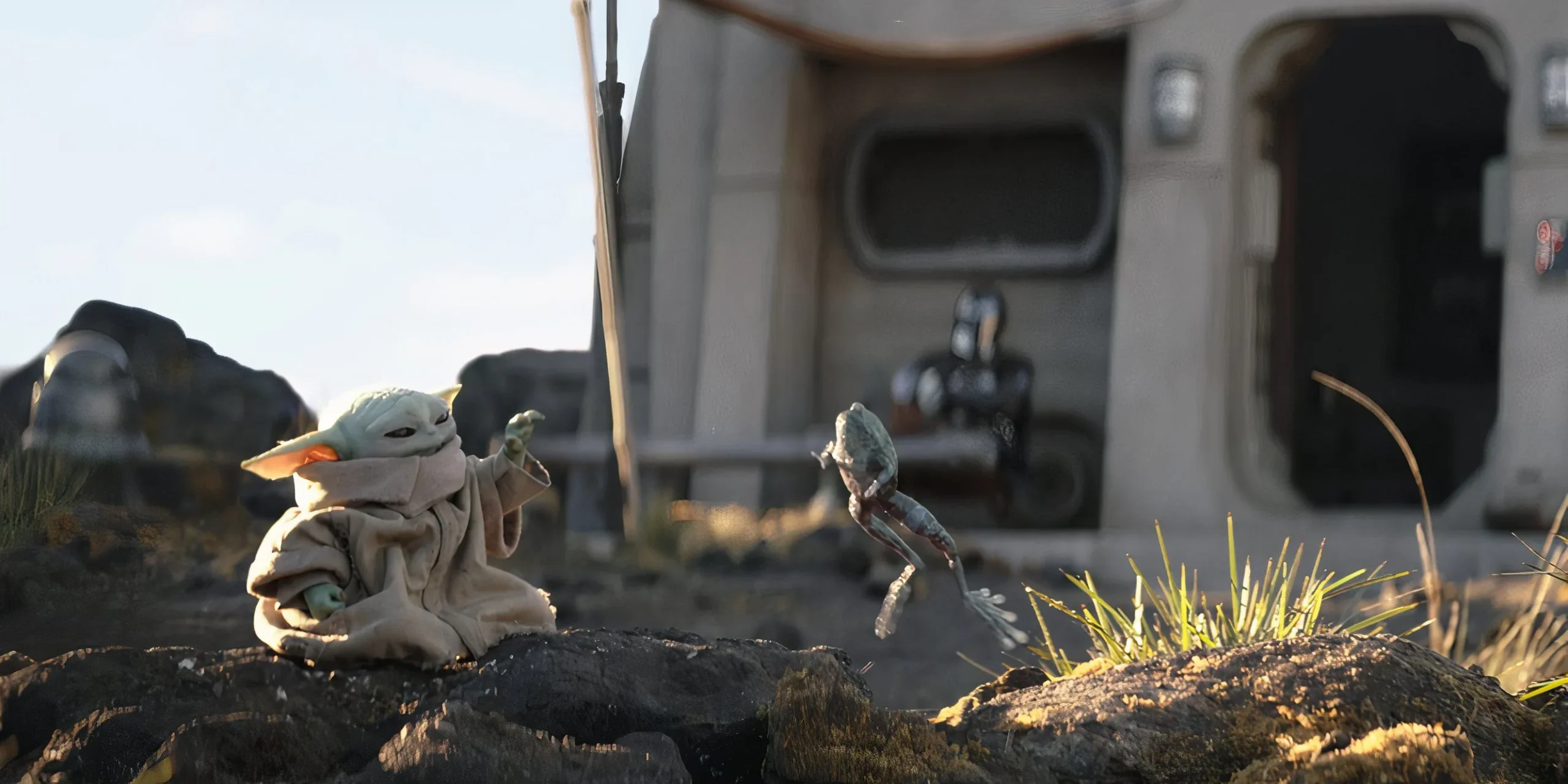 Grogu levitates a frog using the Force while Din Djarin watches in front of their cabin. Grogu levitates a frog using the Force while Din Djarin watches in front of their cabin.