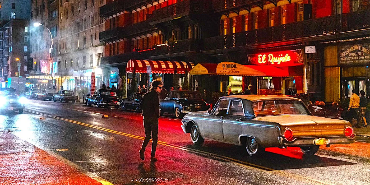 Timothee Chalamet as Bob Dylan crosses a rainy New York street with neon signs reflected on the pavement in a scene from A Complete Unknown Timothee Chalamet as Bob Dylan crosses a rainy New York street with neon signs reflected on the pavement in a scene from A Complete Unknown