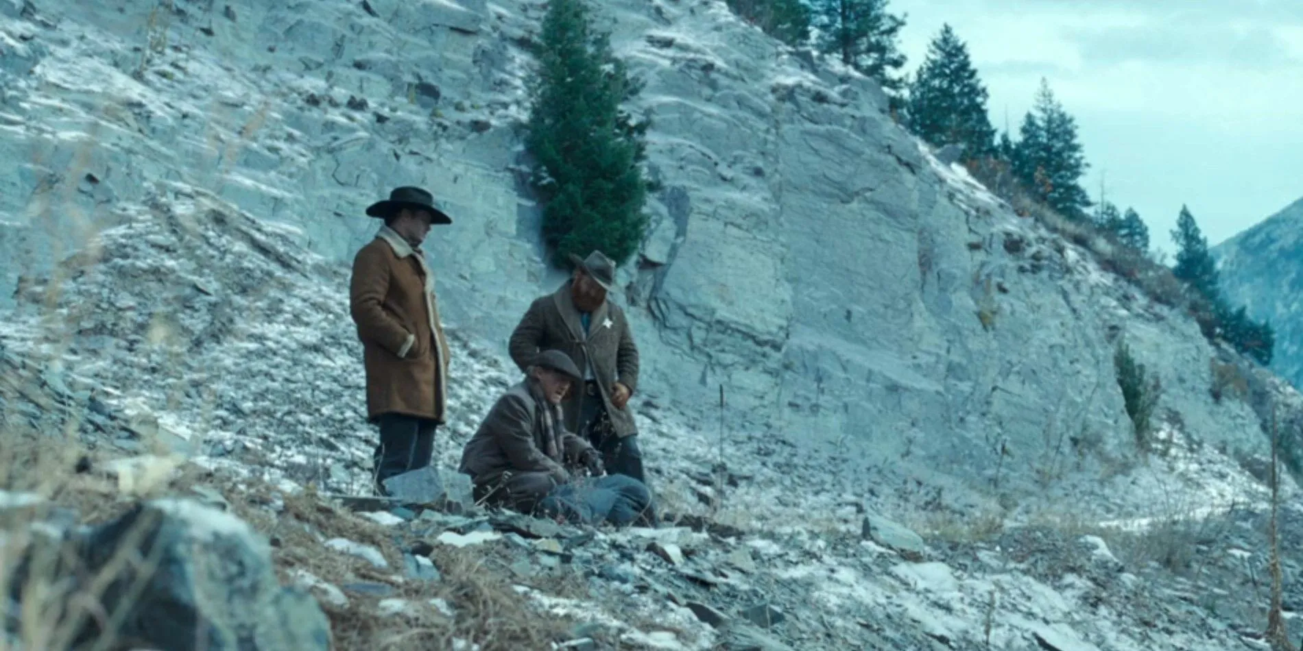Three men surround a dead body wrapped in a blanket at the Train Station in 1923 season 2, episode 5 Three men surround a dead body wrapped in a blanket at the Train Station in 1923 season 2, episode 5