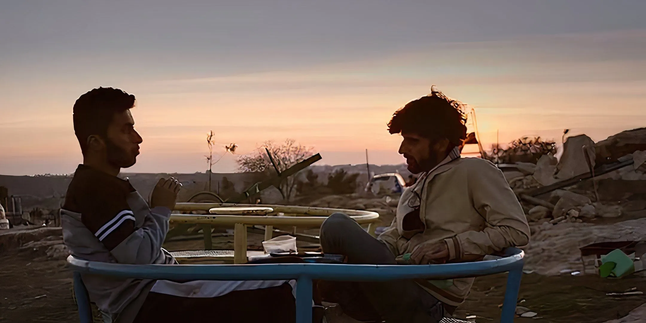 Two men sitting in a small playground feature in No Other Land