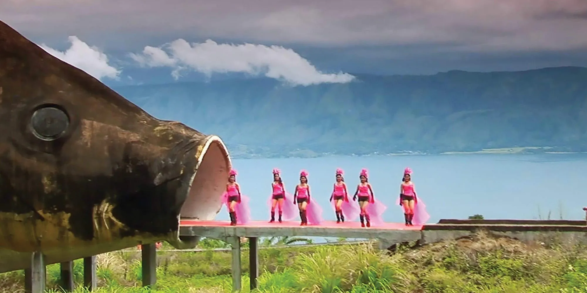 Women in pink dresses pose next to a giant fish from The Act of Killing Women in pink dresses pose next to a giant fish from The Act of Killing