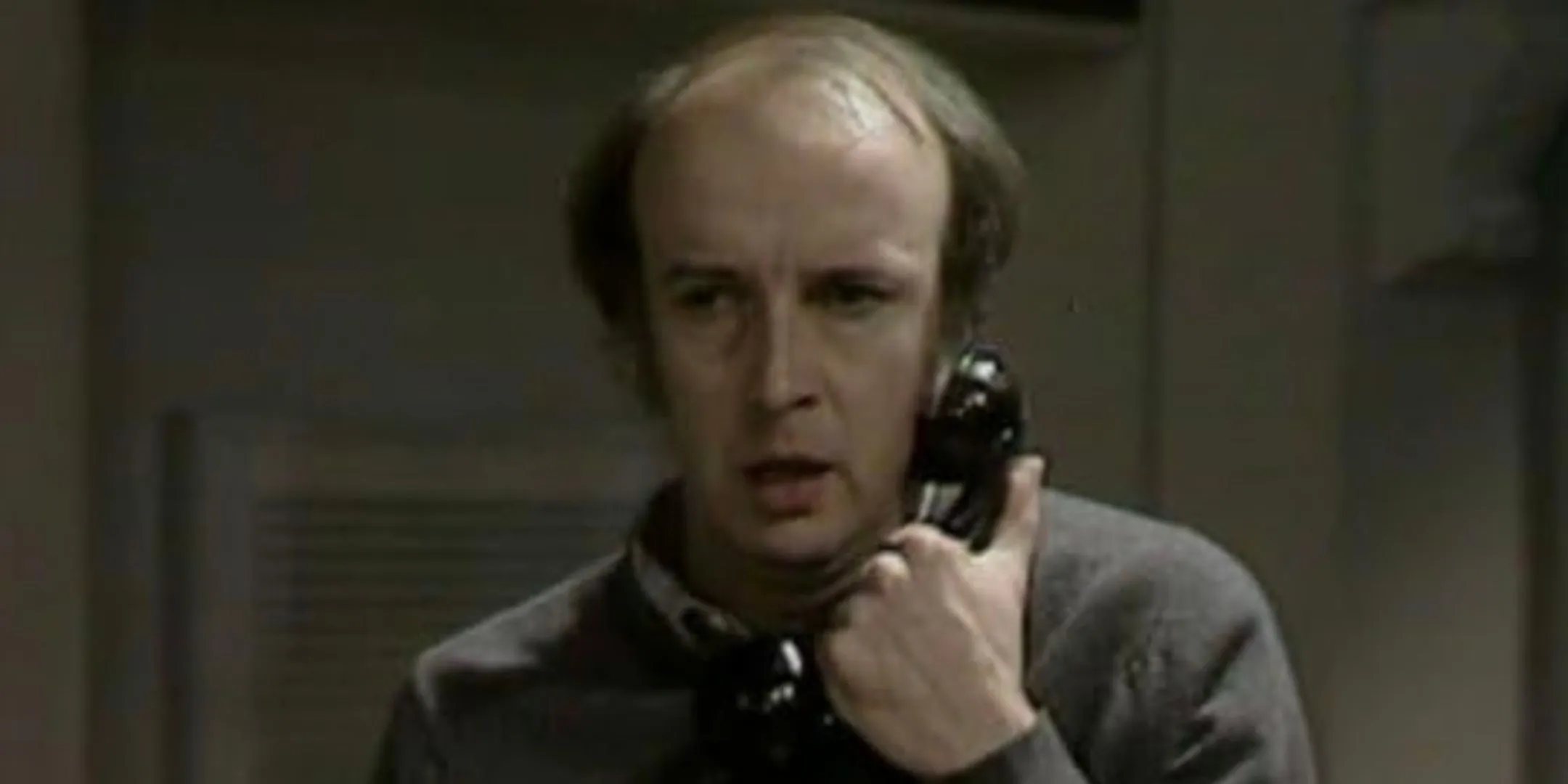 Alan David holds a phone close to his face in shock. Alan David holds a phone close to his face in shock.