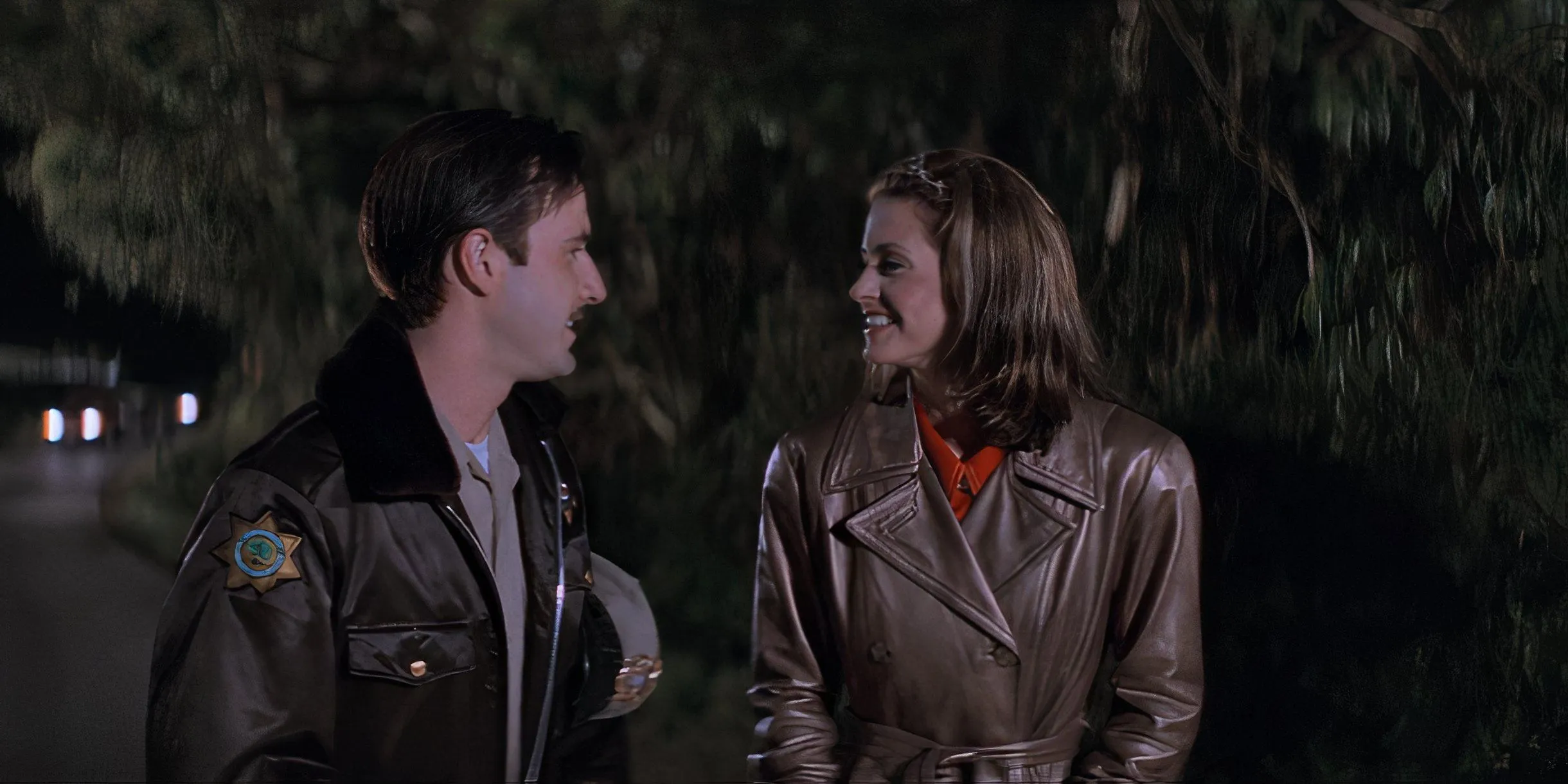 Gale (Courteney Cox) and Dewey (David Arquette) smile at each other as they walk together in Scream (1996). Gale (Courteney Cox) and Dewey (David Arquette) smile at each other as they walk together in Scream (1996).