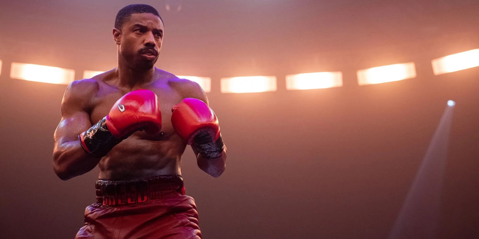 Adonis stands in the ring with his gloves up in Creed III