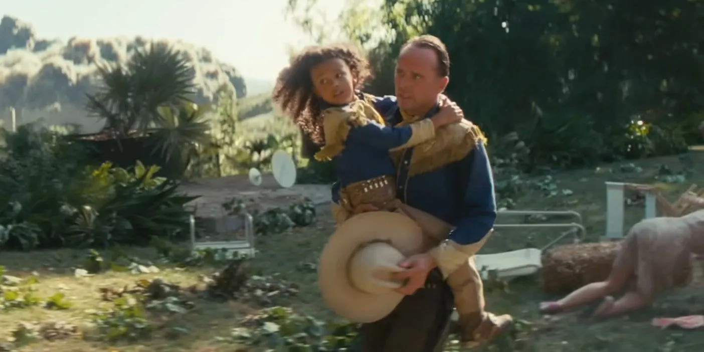 Teagan Meredith as Janey Howard being carried by Walton Goggins as Cooper Howard as the bombs fall in the Fallout show Teagan Meredith as Janey Howard being carried by Walton Goggins as Cooper Howard as the bombs fall in the Fallout show