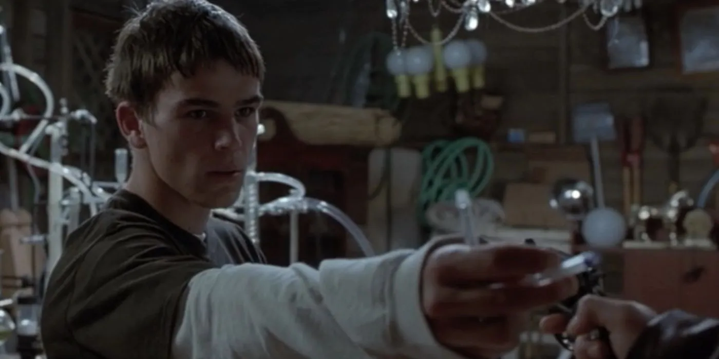 Josh Hartnett's Zeke hands over a pen at gunpoint while frowning in The Faculty