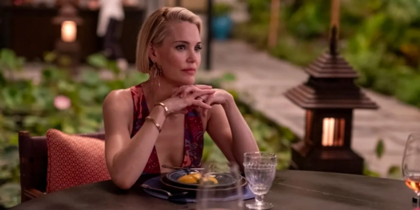 Kate (Leslie Bibb) at a table with her fingers crossed in The White Lotus season 3, episode 7.