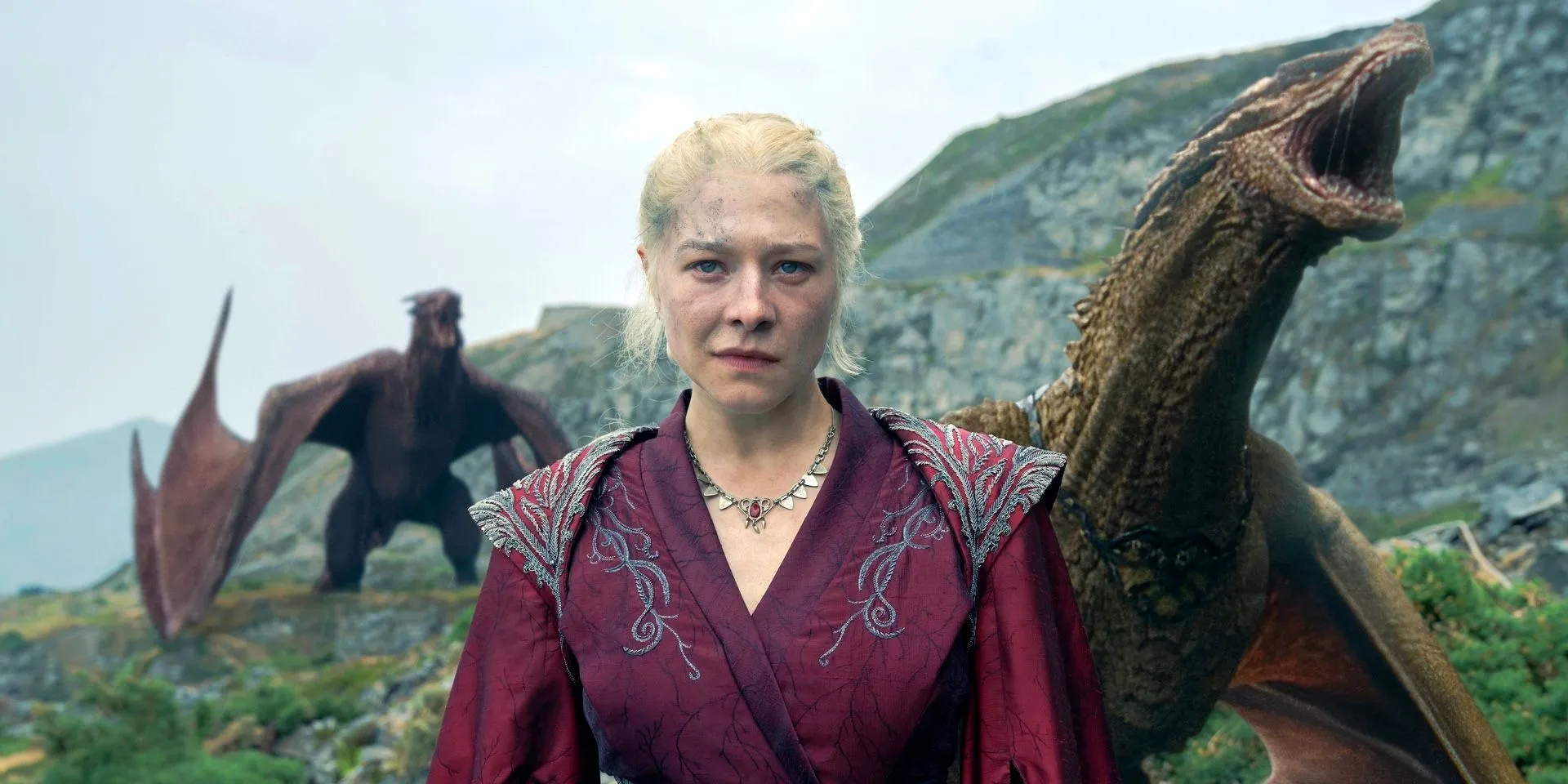 Queen Rhaenyra Targaryen (Emma D'Arcy) smiling with dragons behind her in House of the Dragon