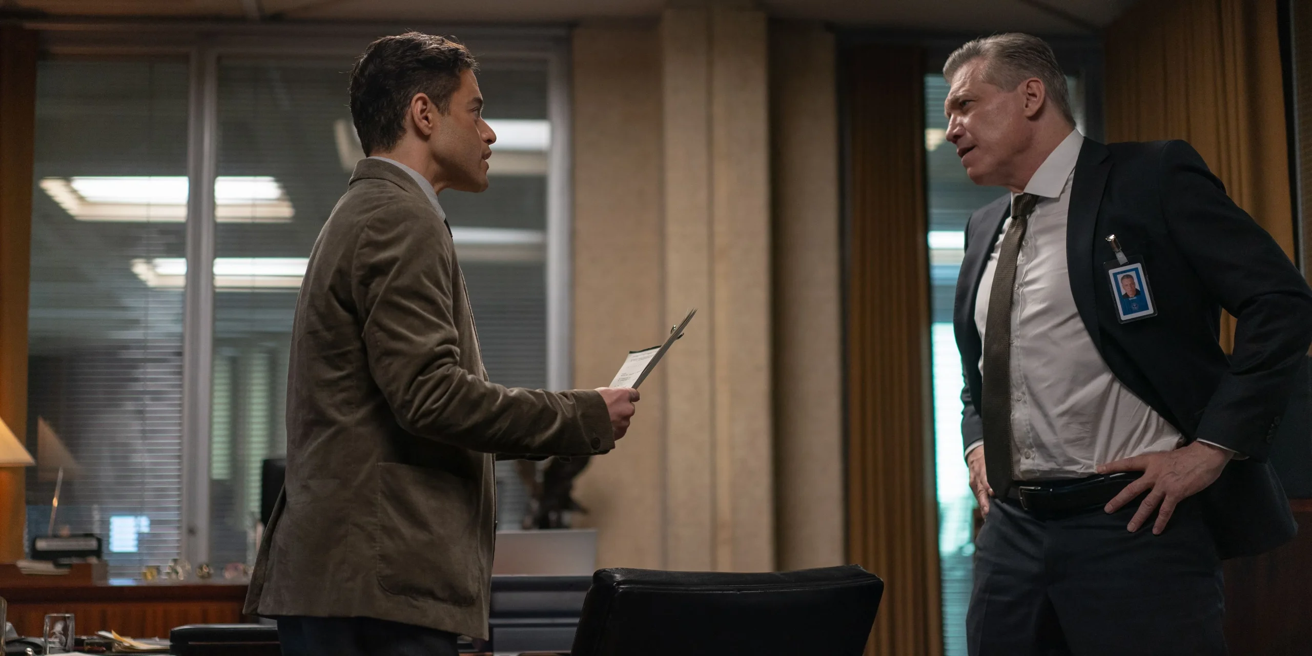 Rami Malek showing files to his boss in The Amateur Rami Malek showing files to his boss in The Amateur
