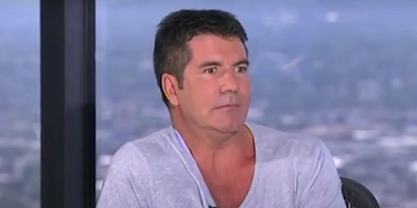 simon cowell cringing on american idol in a blue t-shirt during auditions