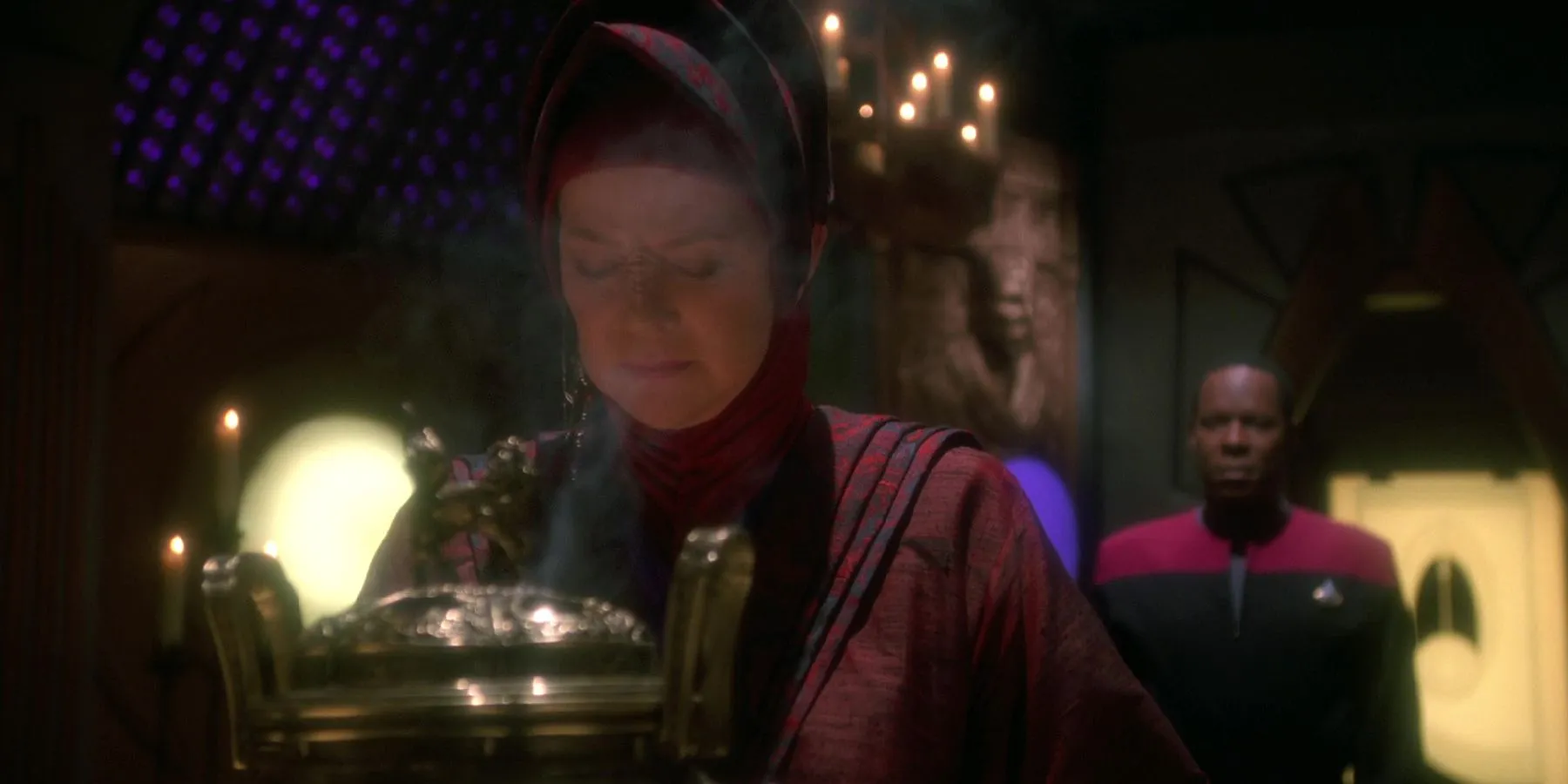 Vedek Winn meditates as Sisko stands behind her Vedek Winn meditates as Sisko stands behind her