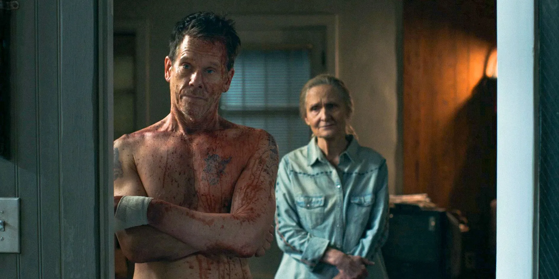 Hub Halloran (Kevin Bacon) covered in blood, with Kitty Halloran (Beth Grant) standing behind him in The Bondsman Season 1 Hub Halloran (Kevin Bacon) covered in blood, with Kitty Halloran (Beth Grant) standing behind him in The Bondsman Season 1
