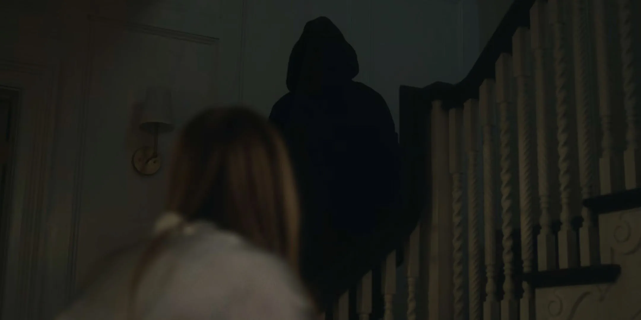A hooded figure standing on the stairs in The Watcher A hooded figure standing on the stairs in The Watcher