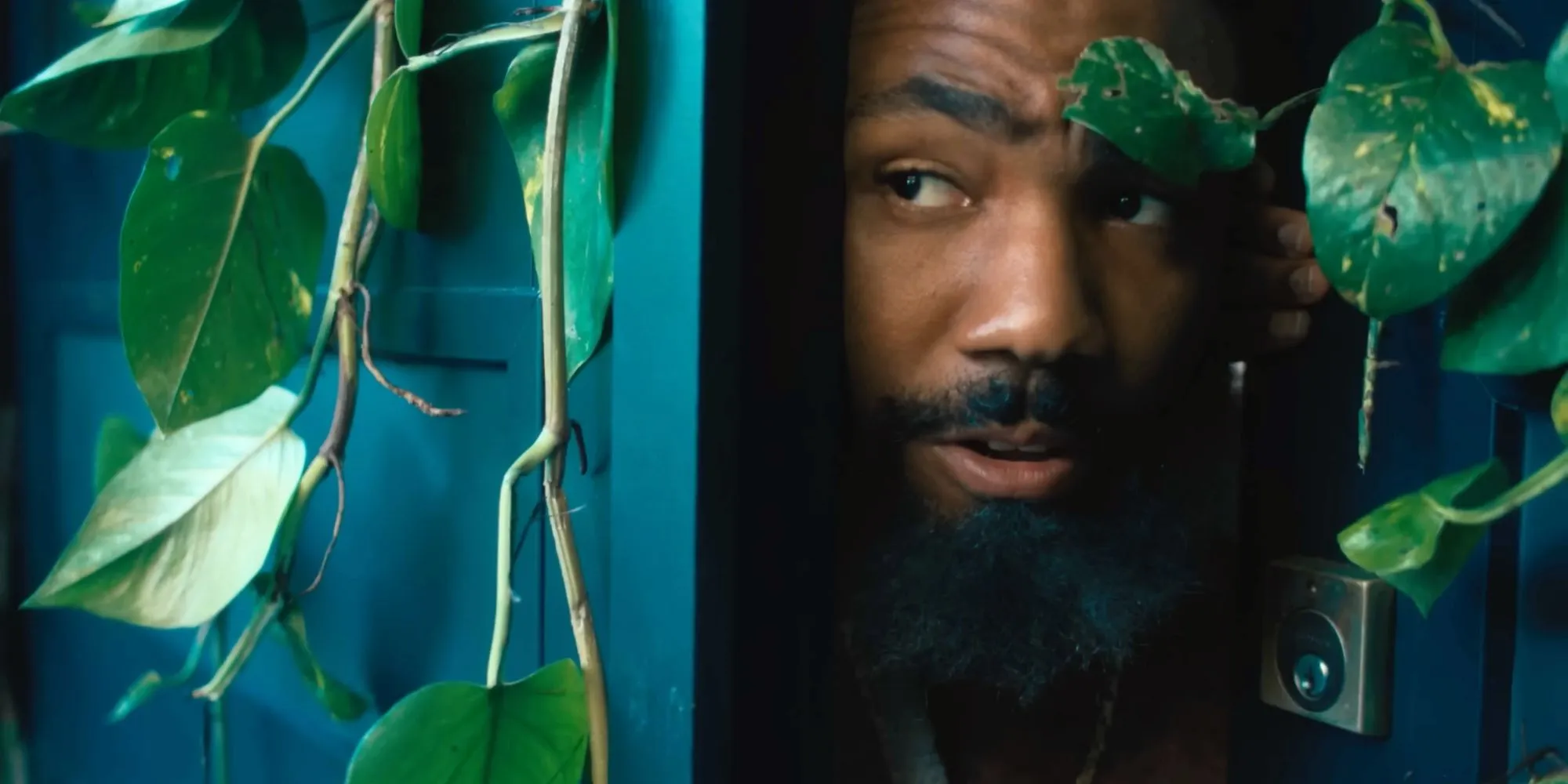 Danny Glover peeking out from a vine-covered doorway in the Bando Stone trailer Danny Glover peeking out from a vine-covered doorway in the Bando Stone trailer