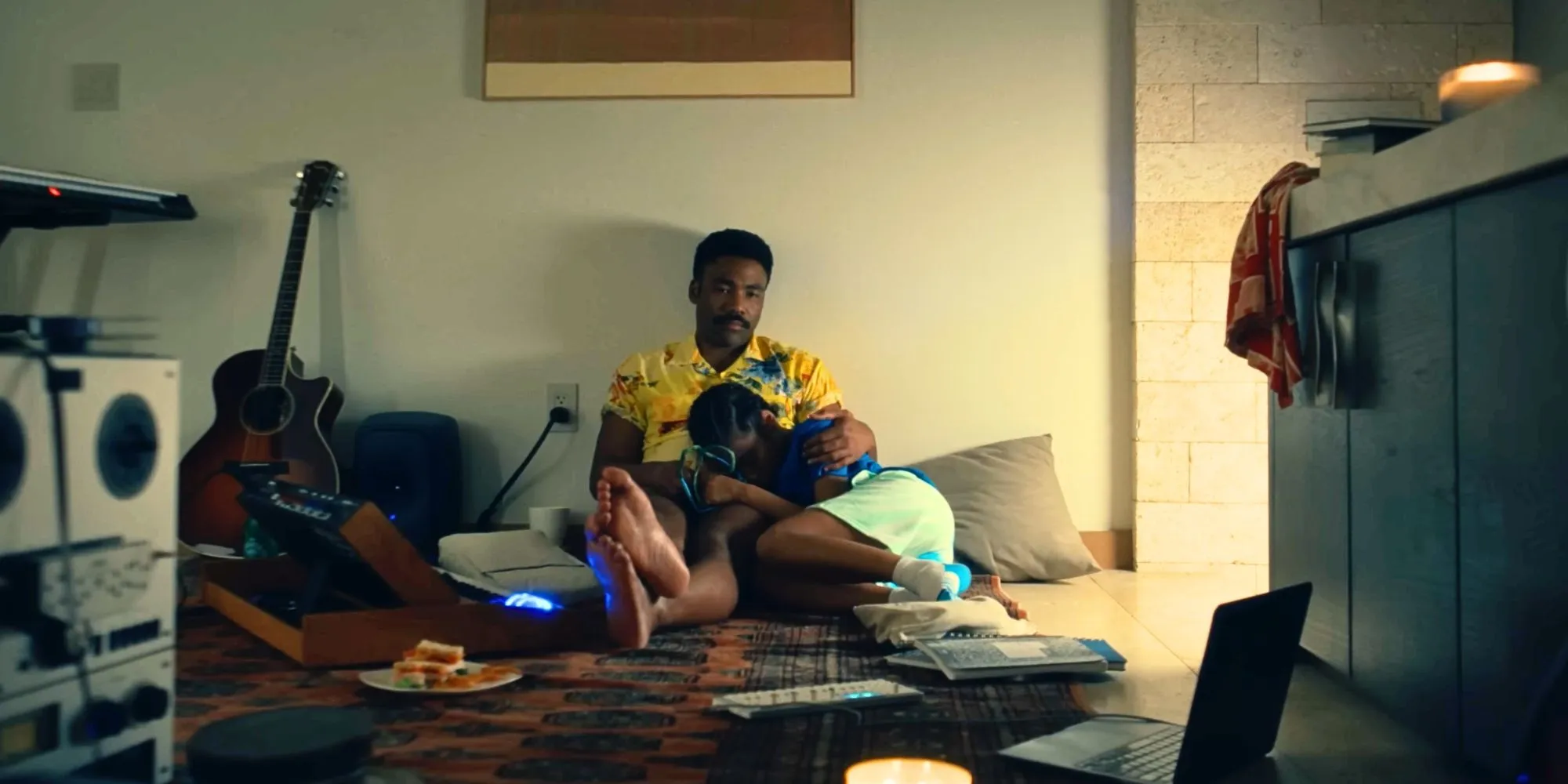 Donald Glover holding Legend while sitting on the floor in the Bando Stone trailer Donald Glover holding Legend while sitting on the floor in the Bando Stone trailer