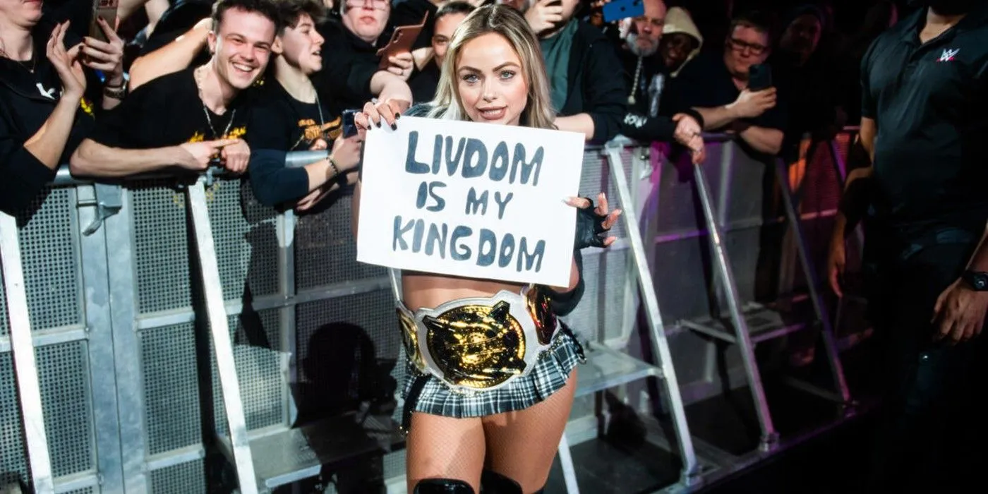 WWE Women's Tag Team Champion Liv Morgan holds up a fan sign at a live event WWE Women's Tag Team Champion Liv Morgan holds up a fan sign at a live event